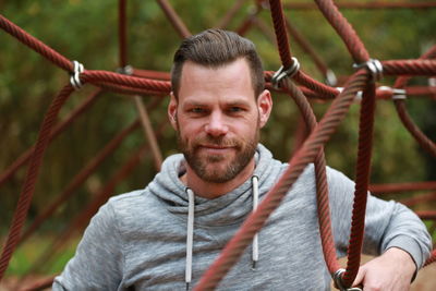 Portrait of man standing amidst jungle gym at playground