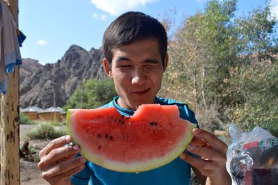 Close-up of man winking while holding watermelon