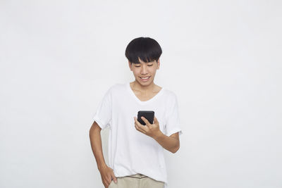 Young man using smart phone against white background