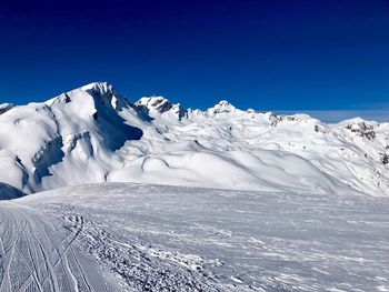 Scenic view of snowcapped mountains against clear blue sky