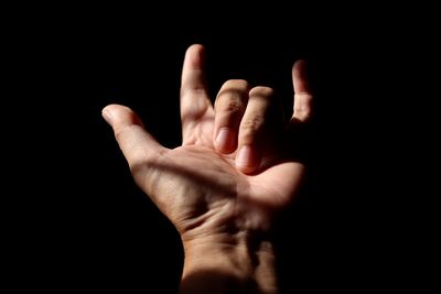 Close-up of hand gesturing against black background