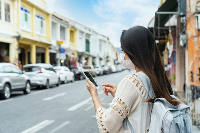 Side view of woman using phone on road