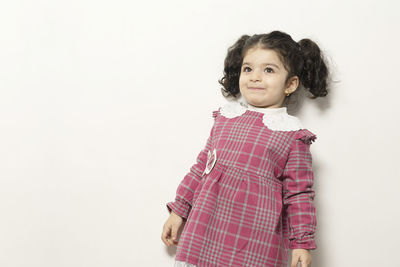 Portrait of cute girl standing against white background