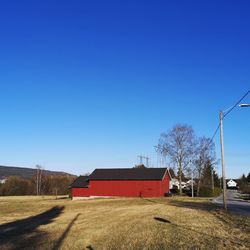 House on field against clear blue sky