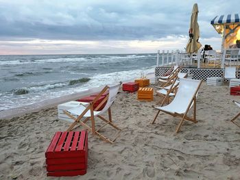 Deck chairs on beach against sky