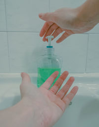 Cropped hands of woman taking liquid at sink