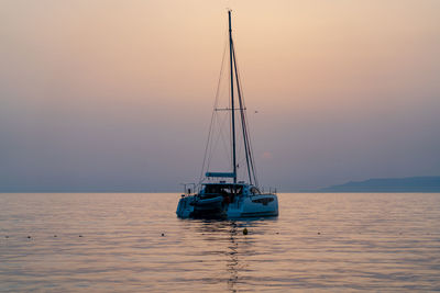 Sailboat sailing on sea against sky during sunset