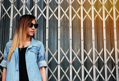 Young woman standing against closed gate