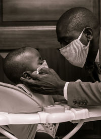 Portrait of father putting on a face mask on his son 