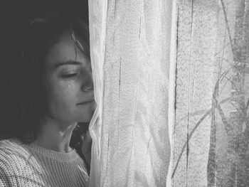 Portrait of young woman looking through window