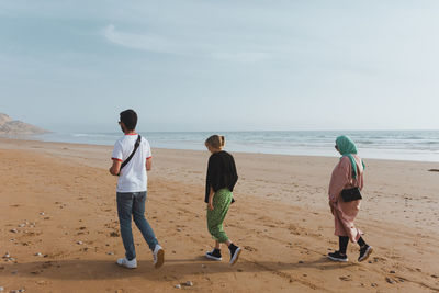 Group of friends walking on the beach, diverse people. morocco