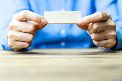 Close-up of man holding paper on table