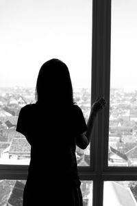 Rear view of woman looking through window