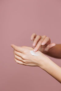 Cropped hand of woman against pink background