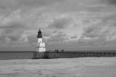 Lighthouse by sea against sky