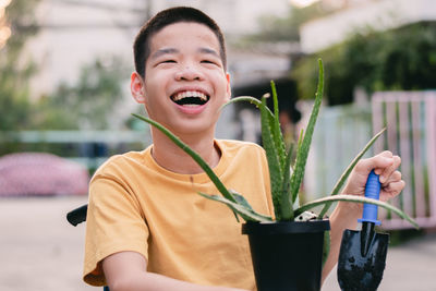 Portrait of smiling disabled boy on the wheelchair  holding plant