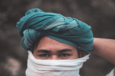 Close-up portrait of man covering face with scarf while wearing turban