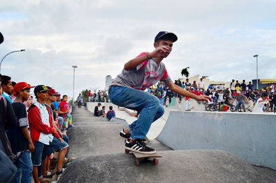 Group of people skateboarding on street against sky