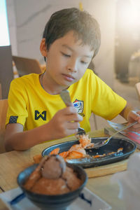 Portrait of boy holding ice cream on table