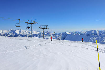 Chairlift and skiers at the ski resort. against the background of snow ridges and blue sky