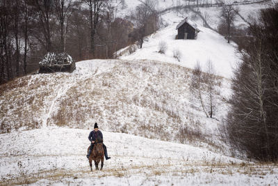 Rear view of man walking on snow covered landscape