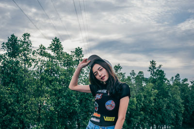 Young woman standing by plants against sky