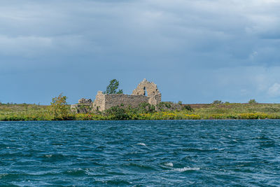 Building by sea against cloudy sky