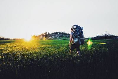 Woman walking on field against clear sky