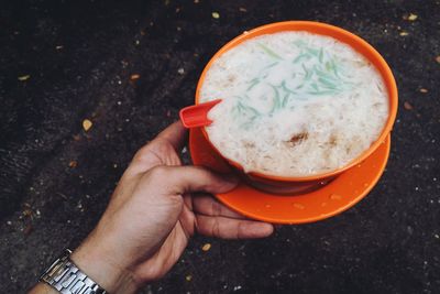 Cropped hand of man holding dessert in bowl at street