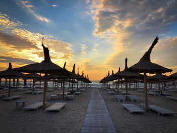 Beautiful sunrise moment on an empty beach with thatched roof umbrellas