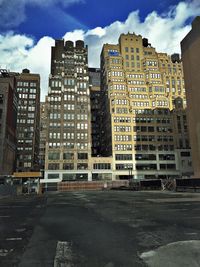 Buildings in city against cloudy sky