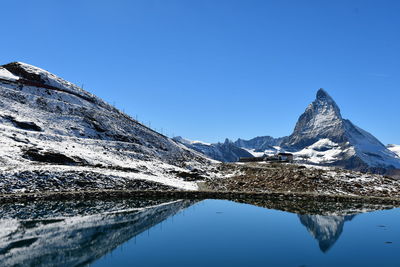 Scenic view of snowcapped mountains against clear blue sky