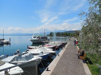 Boats moored at harbor against sky