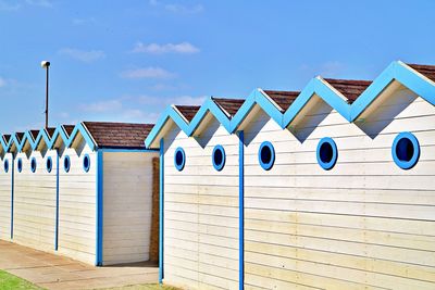 Beach huts against buildings against blue sky