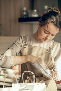 Woman bakery shop owner pours confetti into a bag for customer order. food delivery concept.