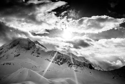 Scenic view of snowcapped mountains against sky with sun