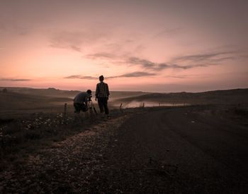 Two men photographing at sunset against sky