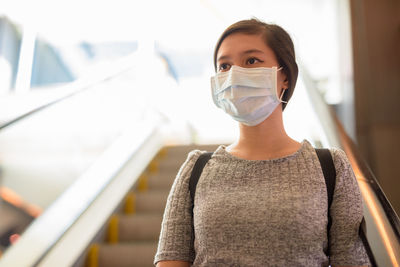 Portrait of young woman standing against blurred background