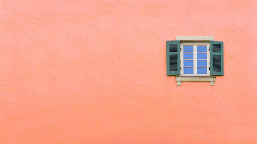 Low angle view of window on pink wall