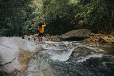 Man standing on rock by river in forest
