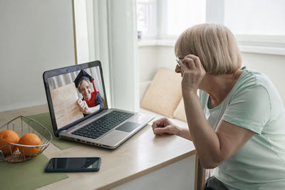 Woman using mobile phone while sitting on table