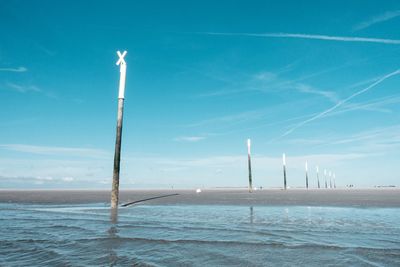 Wooden posts on beach against sky