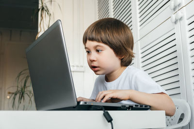 Cute boy using laptop at table