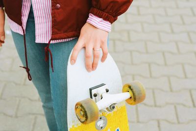Midsection of woman holding skateboard