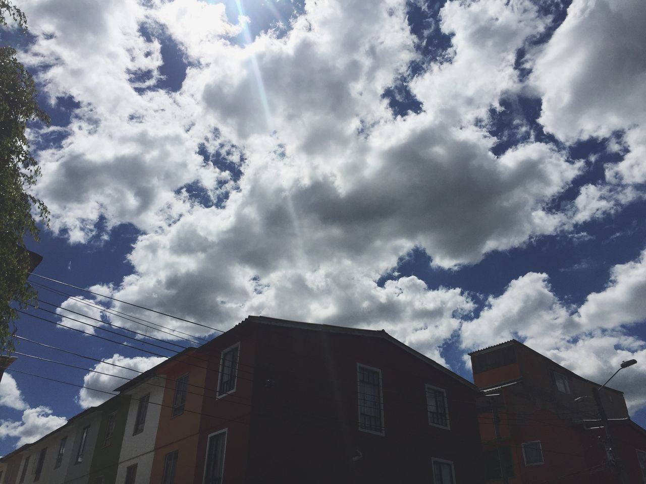 cloud - sky, sky, low angle view, building exterior, weather, architecture, no people, storm cloud, built structure, outdoors, dramatic sky, sunbeam, nature, day, city, tree