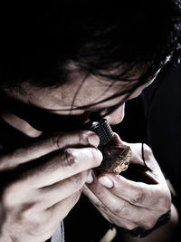 Close-up of man looking at amulet through loupe