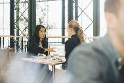 Confident businesswomen planning strategy at table during meeting in cafeteria