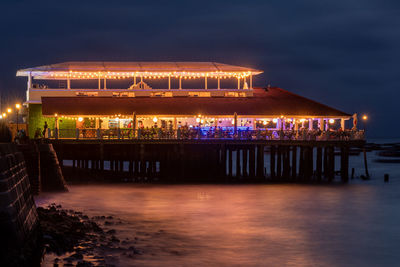 Illuminated built structures in sea at night