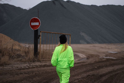 Rear view of woman walking on field against mountain