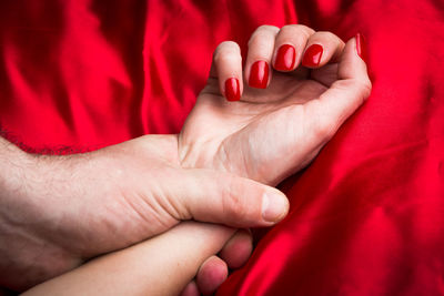 Cropped image of man holding woman hand on bed